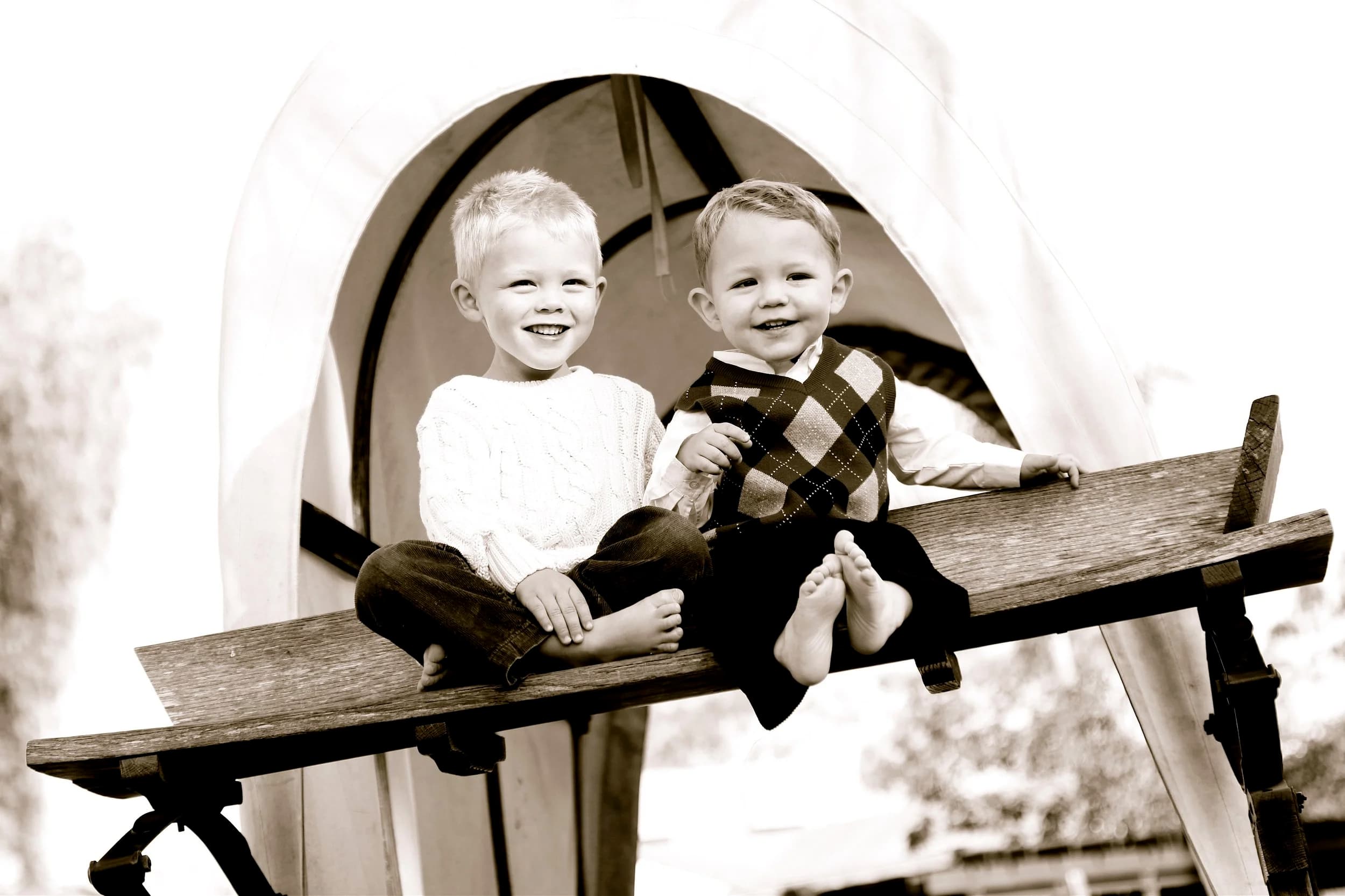 Two young brothers sitting together on a wagon bench, all smiles
